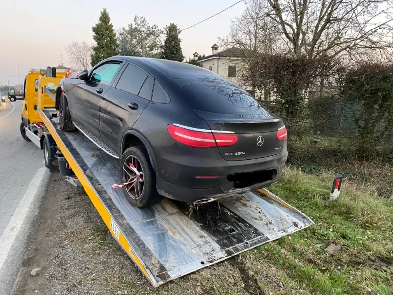 SUV grigio scuro caricato sul pianale inclinato di un carro attrezzi